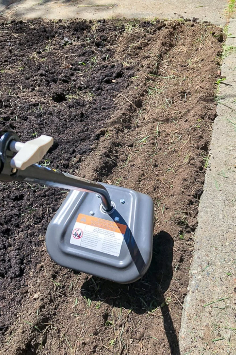mixing compost into cleared garden bed with a cultivator