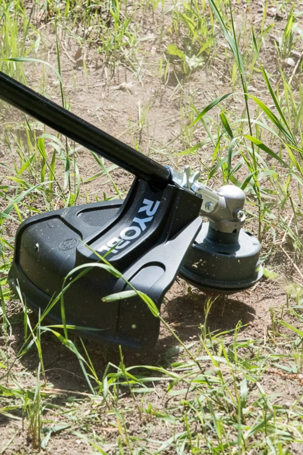 using a string trimmer to cut down weeds in an overgrown flower bed