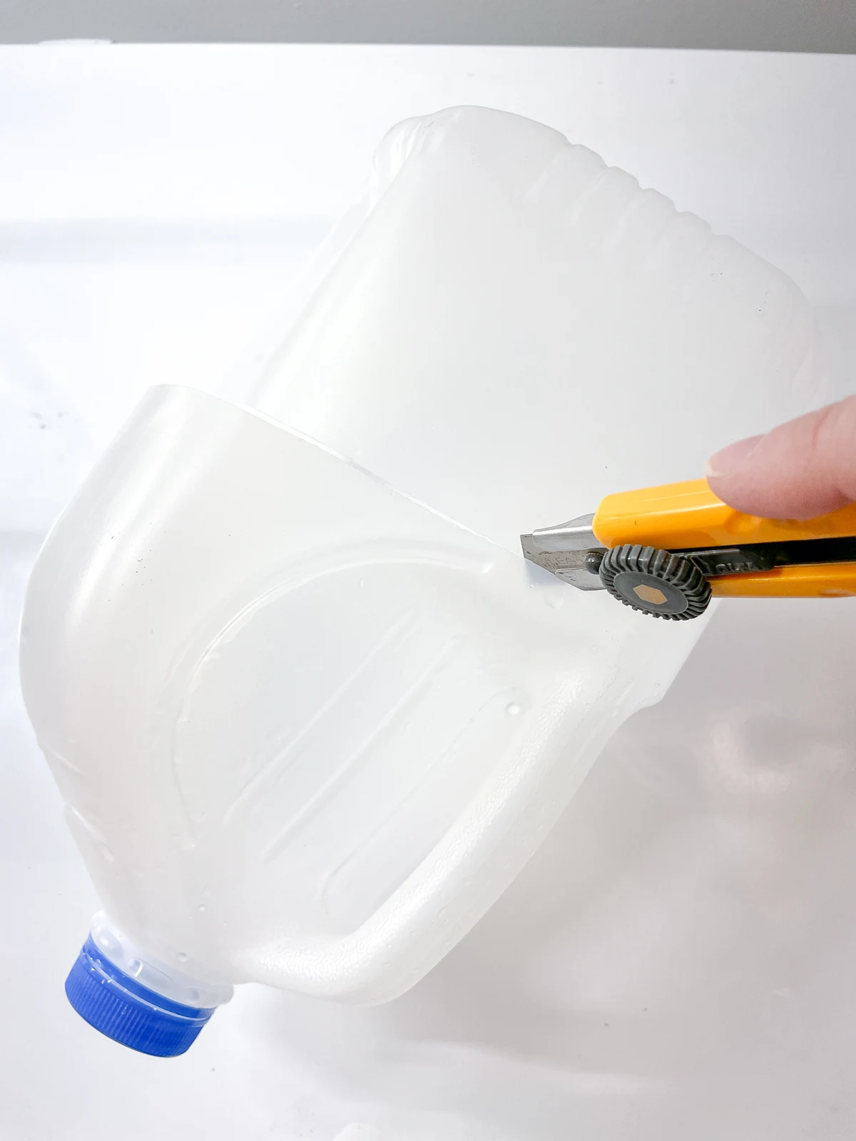 cutting milk jug in half with a box cutter