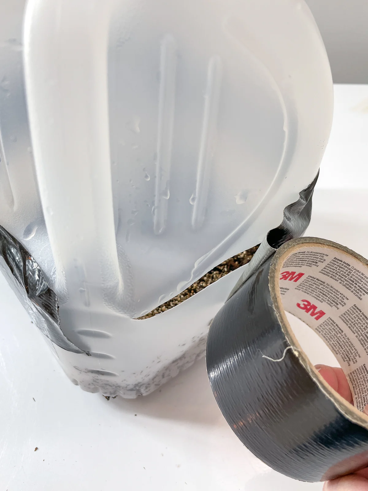 wrapping duct tape around the outside of the milk jug with seeds inside